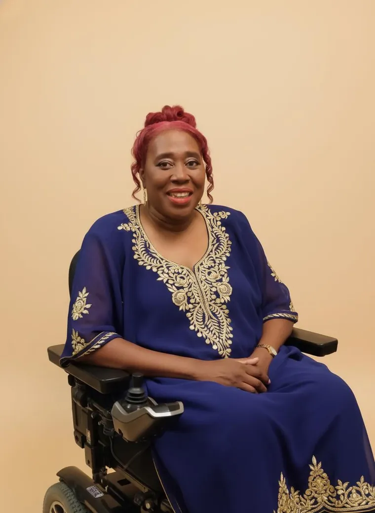 Cynthia Perez, a woman with pink hair in a blue traditional outfit, seated in a power wheelchair